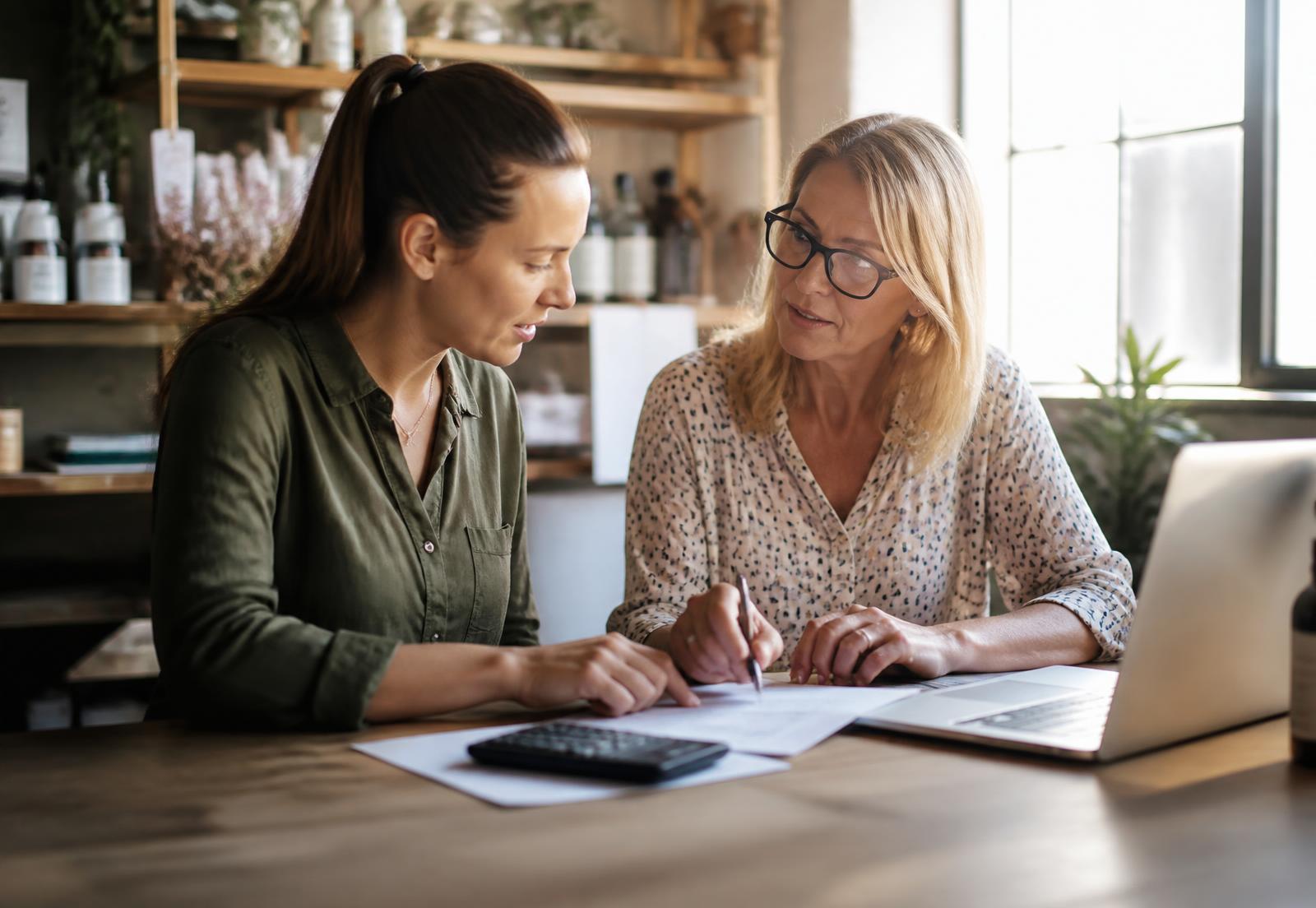 A business owner reviewing records with a bookkeeping professional at a sunlit table